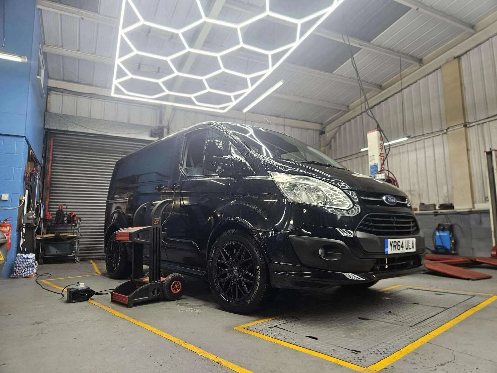 14 Grid with Border Hexagon Lights hung down using 3 metre suspension cables in a MOT garage